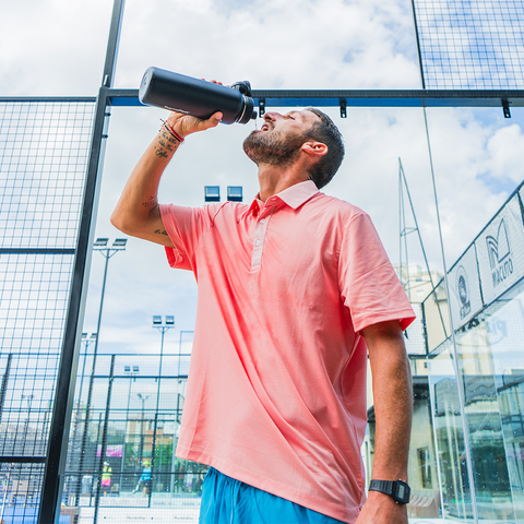 Man drinking from water bottle on tennis court