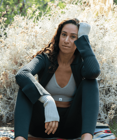 Model sitting on the ground, elbow on her knee, holding her head in a matching activewear outfit
