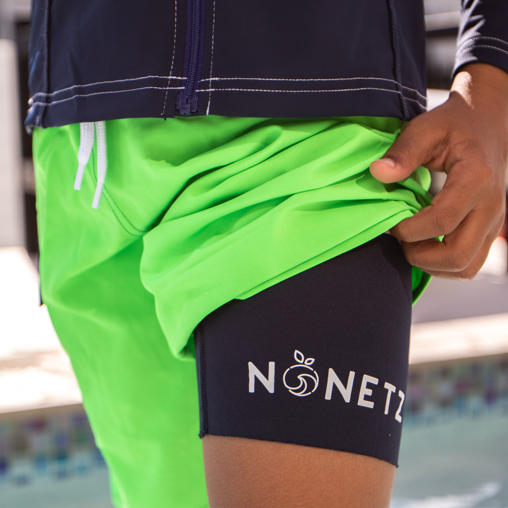 Boy lifting the hem of a swim trunk to show the NoNetz liner.