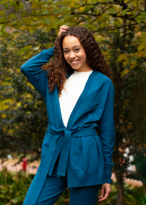 The Women's Callie Long Sleeve Front Tie Sweater in blue worn by a female model outside in a park
