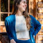 Women's Camille Ribbed Crop Top in an ivory color shown with the blue Callie Front Ties Sweater on a woman in front of a cabin