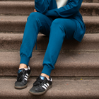 Woman sitting on steps wearing the Charlotte High-Waisted Joggers in peacock blue