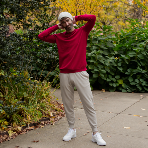 Men's Chase Jogger in tan on a sidewalk in front of bushes wearing a red sweater and a tan hat