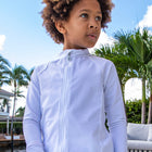Young child dressed in a white long sleeve rash guard with swim shorts