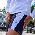 Boy dressed in a white swim shirt paired with blue  and white slim fit swim shorts