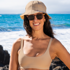 Model standing on the shore in the Women's Suzy Bikini Top in beige with a matching beach hat