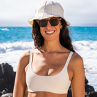 Woman in shades wearing a white sun hat and white bikini top