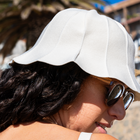 Side of womans face wearing hat and sunglasses at the beach