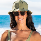Woman wearing a hat, sunglasses and bikini top in front of the ocean
