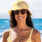Woman wearing sunglasses, a yellow sun hat and matching yellow bikini top
