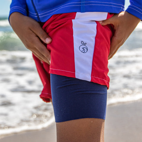 Boy modeling a pair of red and white slim fit swim trunks showing the blue liner