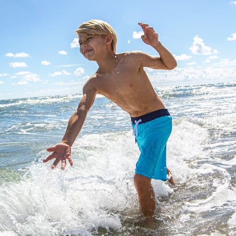 Child playing in the sea wearing Wave swim trunks