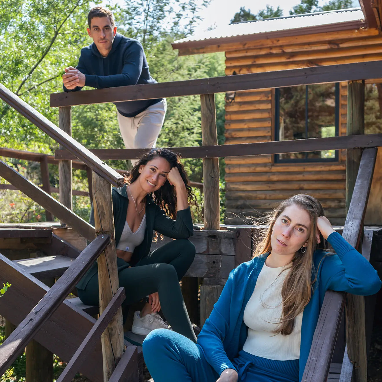 A man and two women hanging out on steps outside of a cabin