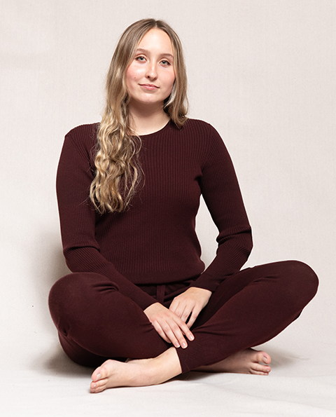 Woman seated wearing maroon long sleeve  sweater and matching joggers