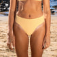 Waist down pic of a woman in a gold bikini at the beach fashion sustainable