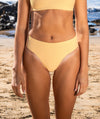 Waist down pic of a woman in a gold bikini at the beach