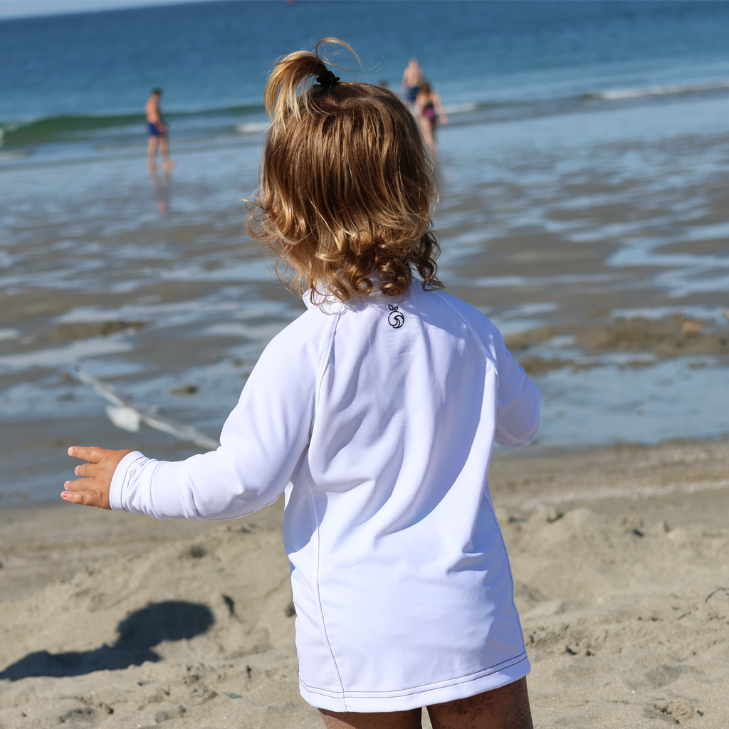 Back of a small child wearing a NoNetz white rashguard at the beach.