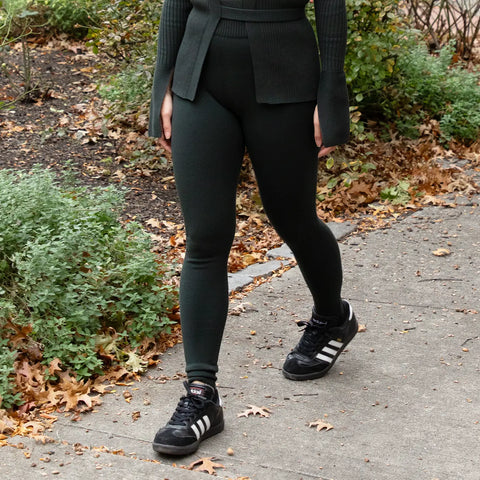 Woman outfitted in green no drawstring joggers paired with a green sweater walking outside on a sidewalk