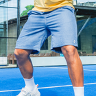 Men's blue Haven Swim Trunks paired with a yellow polo on a tennis court for a sporty look