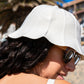 Side of womans face wearing hat and sunglasses at the beach