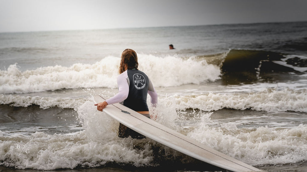 Man walking out into the ocean with a surf board