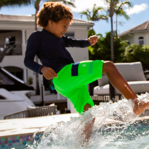 Boy leaping into a swimming pool wearing NoNetz swim trunks