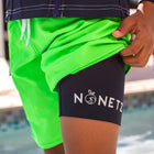 Male model wearing green NoNetz swim trunks showing liner with logo