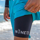 Boy at the beach in blue NoNetz swim shorts showing liner with logo detail