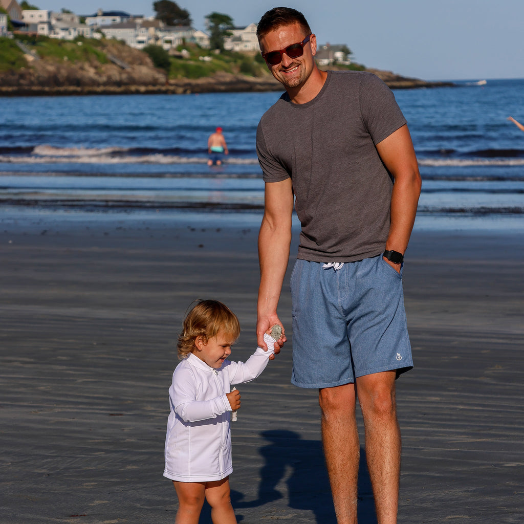 Model and a child on the beach. Man wearing Men's Haven Regular Fit 8" Inseam Swim Trunks ; Child wearing a white NoNetz Rashguard