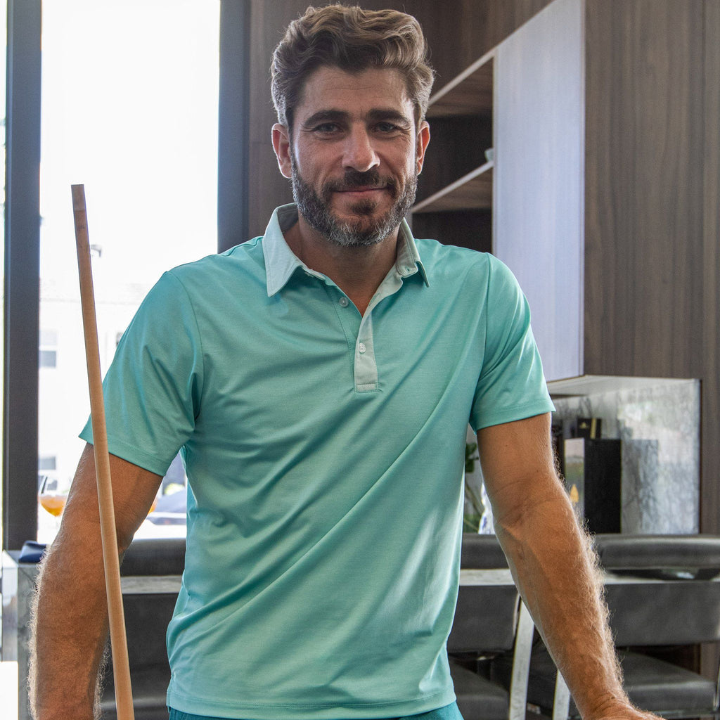 Man wearing a green polo holding a pool stick